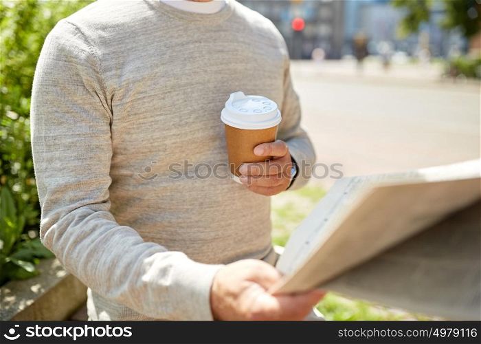 old age and people concept - senior man with coffee reading newspaper sitting on street bench. senior man with coffee reading newspaper outdoors