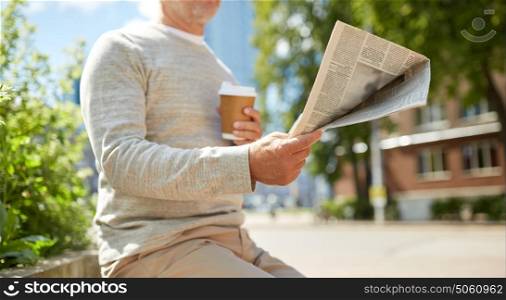 old age and people concept - senior man with coffee reading newspaper sitting on street bench. senior man with coffee reading newspaper outdoors