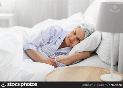 old age and people concept - senior woman lying in bed at home bedroom. senior woman lying in bed at home bedroom