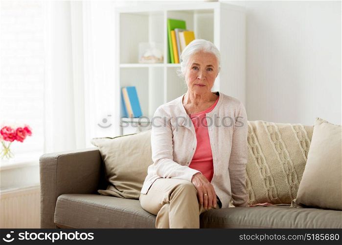 old age and people concept - senior woman sitting on sofa at home. senior woman at home