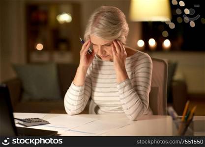 old age and stress concept - stressed senior woman filling tax form at home in evening. senior woman filling tax form at home in evening