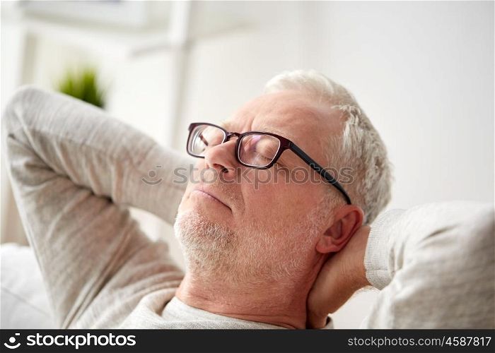 old age, comfort and people concept - senior man in glasses relaxing on sofa at home