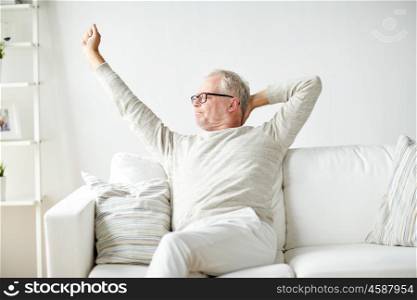 old age, comfort and people concept - senior man in glasses relaxing on sofa at home