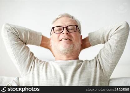 old age, comfort and people concept - smiling senior man in glasses relaxing on sofa at home