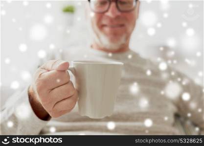 old age, drink and people concept - happy senior man with cup of tea or coffee at home over snow. happy senior man with cup of tea or coffee at home