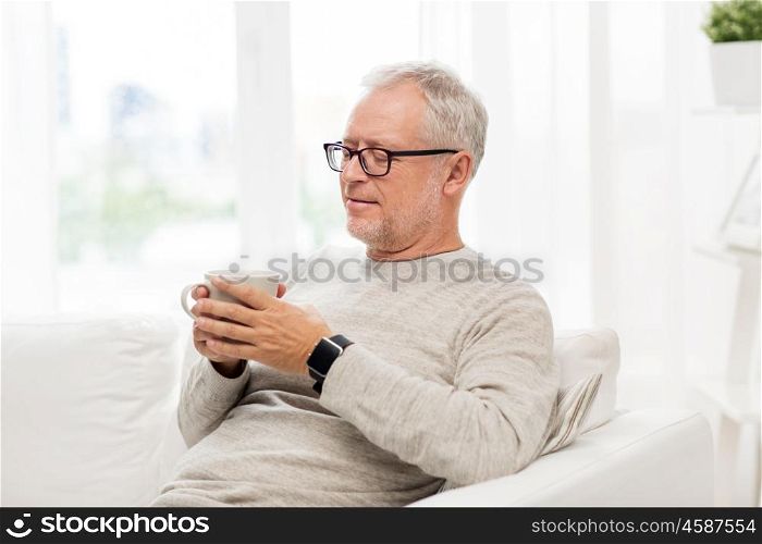 old age, drink and people concept - happy senior man with cup of tea at home