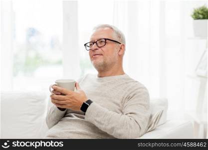 old age, drink and people concept - happy senior man with cup of tea at home