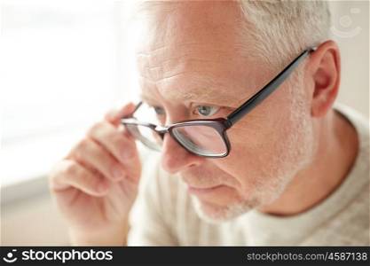 old age, eyesight, vision, optic and people concept - close up of senior man in glasses looking