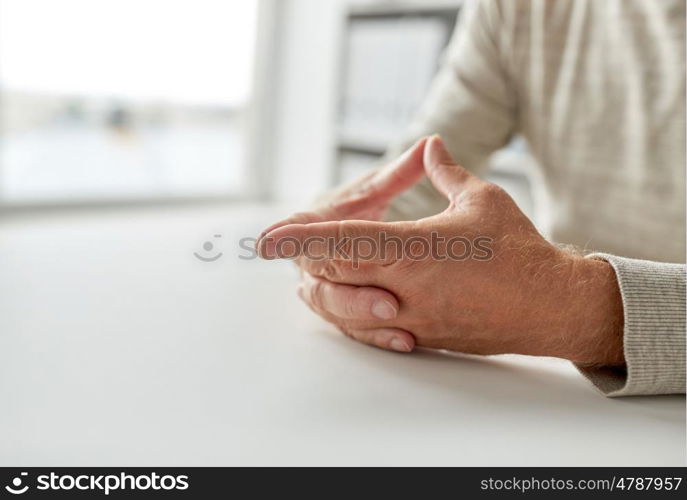 old age, gesture and people concept - close up of senior man hands on table