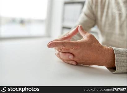 old age, gesture and people concept - close up of senior man hands on table