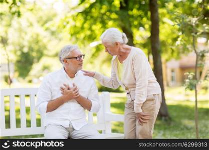old age, health problem and people concept - senior man feeling sick at summer park with his wife. senior man feeling sick at summer park