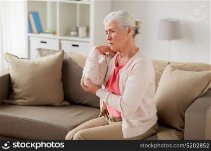 old age, health problem and people concept - senior woman suffering from pain in hand at home. senior woman suffering from pain in hand at home