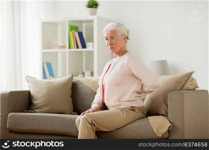 old age, health problem and people concept - senior woman suffering from pain in back or reins at home. senior woman suffering from pain in back at home