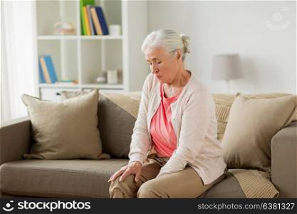 old age, health problem and people concept - senior woman suffering from pain in leg at home. senior woman suffering from pain in leg at home