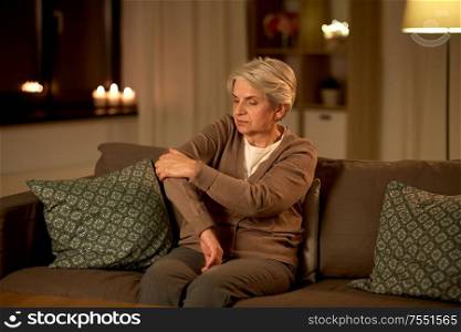 old age, health problem and people concept - senior woman suffering from pain in hand at home at night. senior woman suffering from pain in hand at home