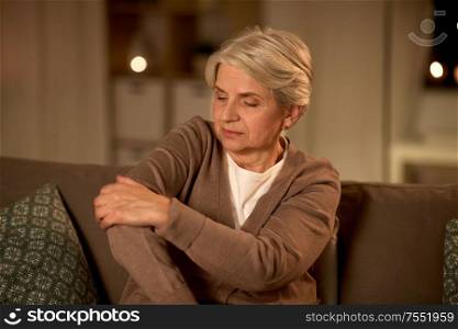 old age, health problem and people concept - senior woman suffering from pain in hand at home at night. senior woman suffering from pain in hand at home