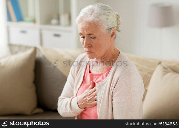 old age, health problem and people concept - senior woman suffering from heartache at home. senior woman suffering from heartache at home