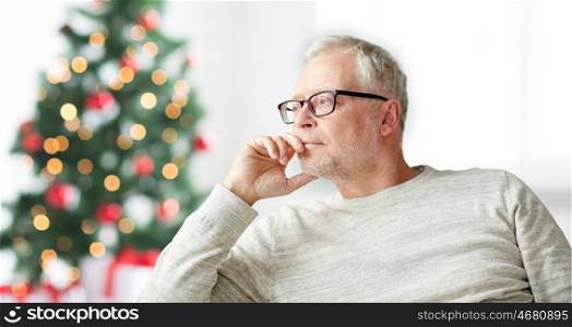 old age, holidays, problem and people concept - senior man in glasses thinking at home over christmas tree background