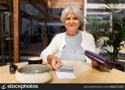 old age, leisure, payment and finances concept - happy senior woman with credit card and wallet paying bill for coffee and dessert at street cafe. senior woman with credit card paying bill at cafe