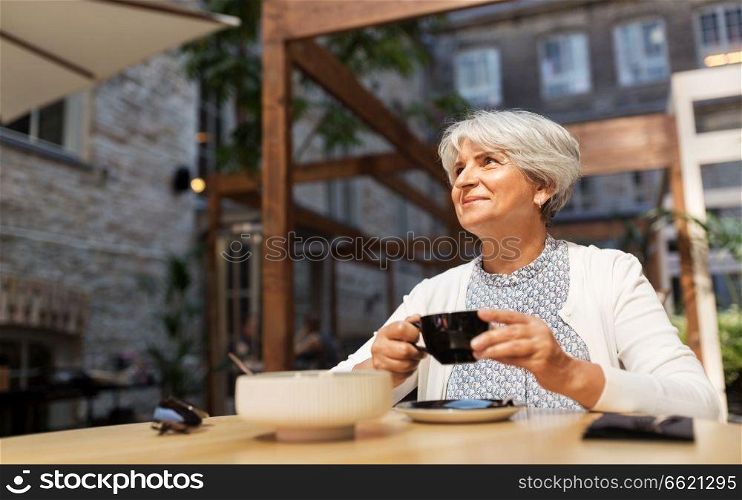 old age, leisure, retirement and people concept - happy senior woman drinking coffee at street cafe. senior woman drinking coffee at street cafe