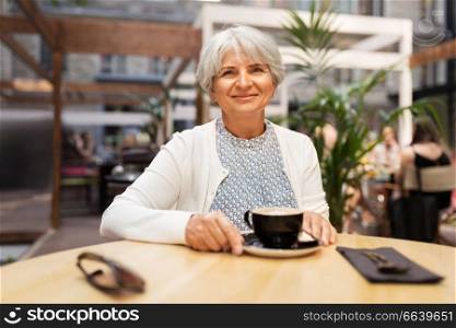 old age, leisure, retirement and people concept - happy senior woman with coffee at street cafe. senior woman with coffee at street cafe