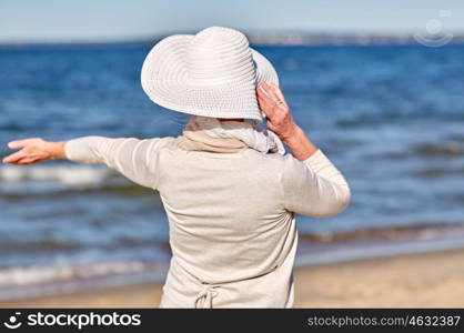 old age, leisure, travel, tourism and people concept - happy senior woman in sun hat on summer beach