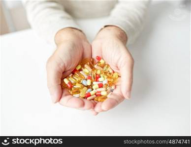 old age, medicine, drugs, healthcare and people concept - close up of senior man hands holding pills