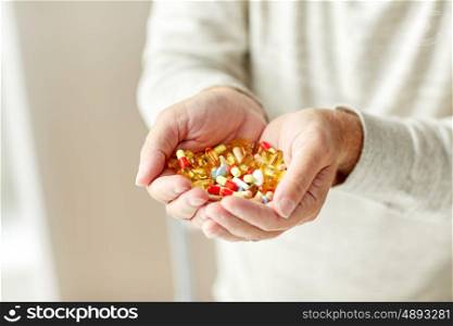 old age, medicine, drugs, healthcare and people concept - close up of senior man hands holding pills