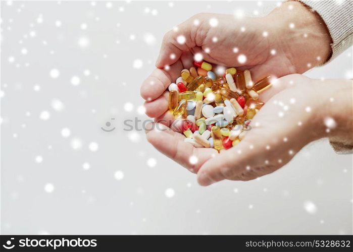 old age, medicine, drugs, healthcare and people concept - close up of senior man hands holding pills over snow. close up of old man hands holding medicine