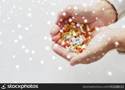 old age, medicine, drugs, healthcare and people concept - close up of senior man hands holding pills over snow. close up of old man hands holding medicine