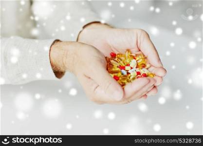 old age, medicine, drugs, healthcare and people concept - close up of senior man hands holding pills over snow. close up of senior man hands holding pills