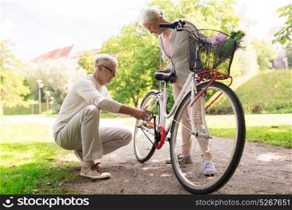 old age, people and lifestyle concept - happy senior couple with fixie bicycle at summer city park. happy senior couple with bicycle at summer park