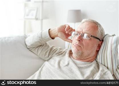 old age, problem and people concept - close up of senior man in glasses thinking at home