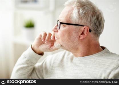 old age, problem and people concept - close up of senior man in glasses thinking at home