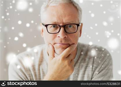 old age, problem and people concept - close up of senior man in glasses thinking over snow. close up of senior man in glasses thinking