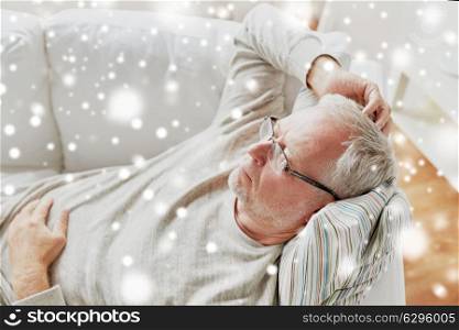 old age, problem and people concept - close up of senior man in glasses lying on sofa and thinking at home over snow. close up of senior man in glasses thinking at home