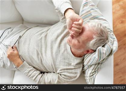 old age, problem and people concept - close up of tired senior man lying on sofa at home