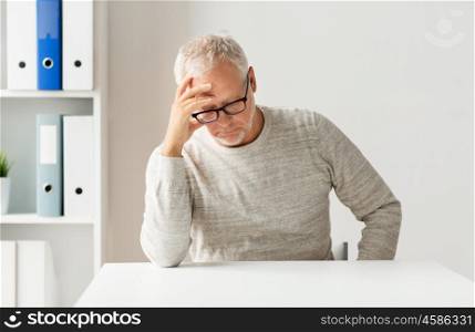 old age, problem, health care and people concept - sad senior man sitting at table at medical office