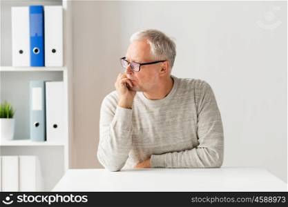 old age, problem, health care and people concept - sad senior man sitting at table at medical office