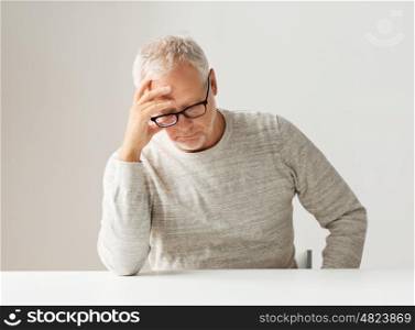 old age, problem, health care and people concept - sad senior man sitting at table