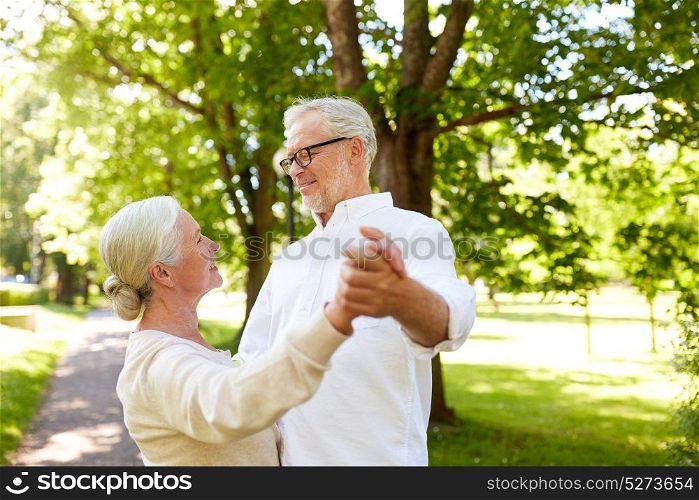 old age, relationship and people concept - happy senior couple dancing waltz at summer city park. happy senior couple dancing at summer city park