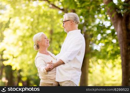 old age, relationship and people concept - happy senior couple dancing waltz at summer park. happy senior couple dancing at summer park