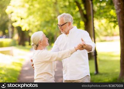 old age, relationship and people concept - happy senior couple dancing waltz at summer park. happy senior couple dancing at summer park