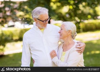 old age, relationship and people concept - happy senior couple hugging at summer park. happy senior couple hugging at summer park