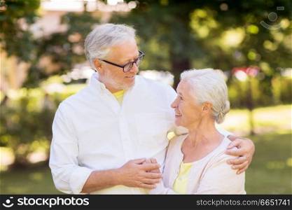 old age, relationship and people concept - happy senior couple hugging at summer park. happy senior couple hugging at summer park