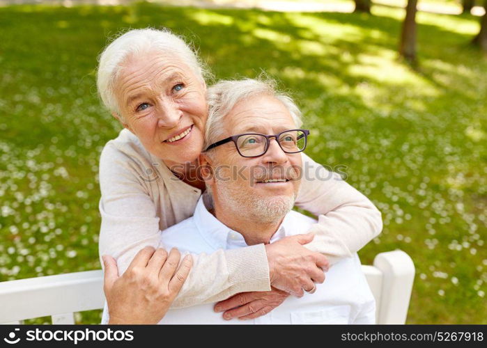 old age, relationship and people concept - happy senior couple hugging in city park. happy senior couple hugging in city park