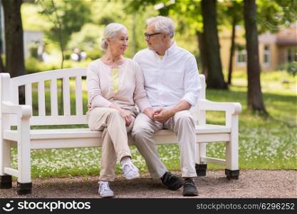 old age, relationship and people concept - happy senior couple sitting on bench at summer park. happy senior couple sitting on bench at park