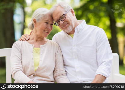 old age, relationship and people concept - happy senior couple sitting on bench at summer park. happy senior couple sitting on bench at park