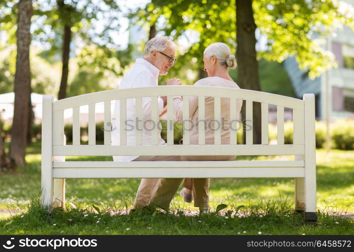 old age, relationship and people concept - happy senior couple sitting on bench at summer park. happy senior couple sitting on bench at park