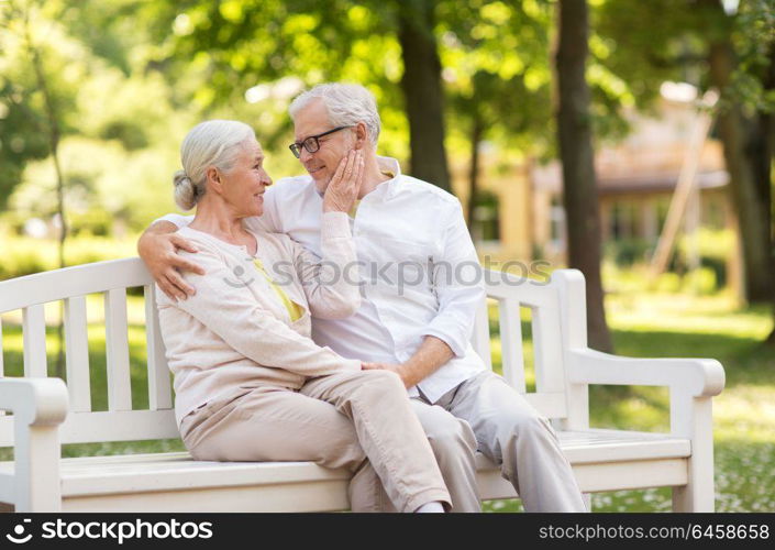 old age, relationship and people concept - happy senior couple sitting on bench at summer park. happy senior couple sitting on bench at park